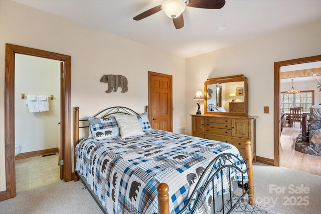 carpeted bedroom featuring connected bathroom and ceiling fan with notable chandelier