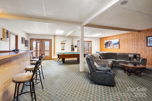 game room with wooden walls, beamed ceiling, carpet floors, a drop ceiling, and french doors