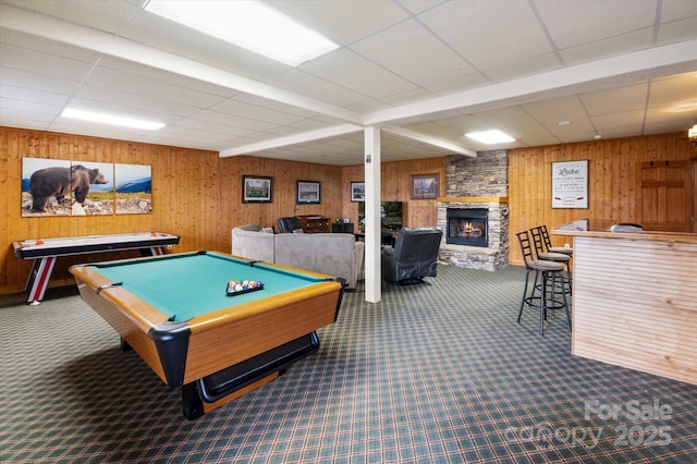 recreation room with a stone fireplace, a paneled ceiling, billiards, wood walls, and carpet flooring