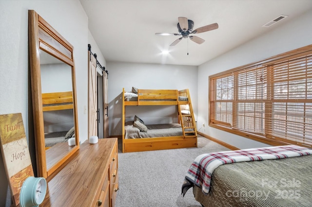 carpeted bedroom with a barn door and ceiling fan