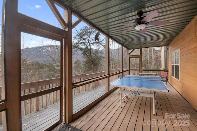 unfurnished sunroom with ceiling fan and a mountain view