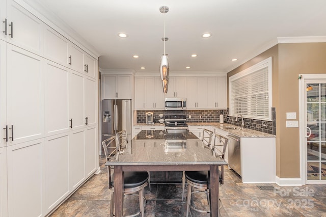 kitchen featuring white cabinetry, light stone countertops, decorative light fixtures, and stainless steel appliances