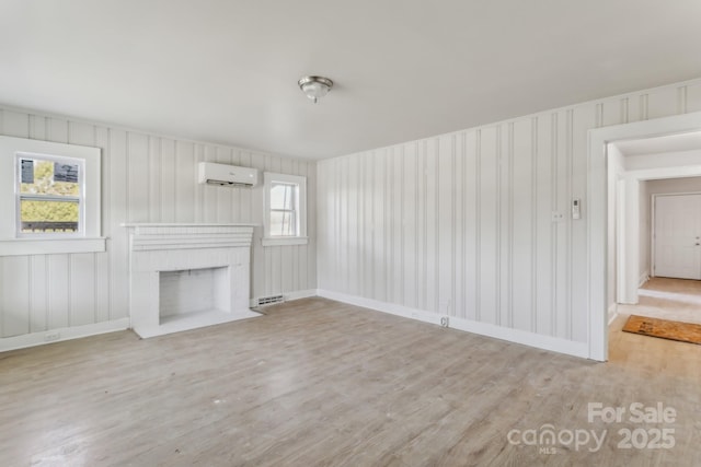 unfurnished living room featuring a brick fireplace, a wall unit AC, and light wood-type flooring