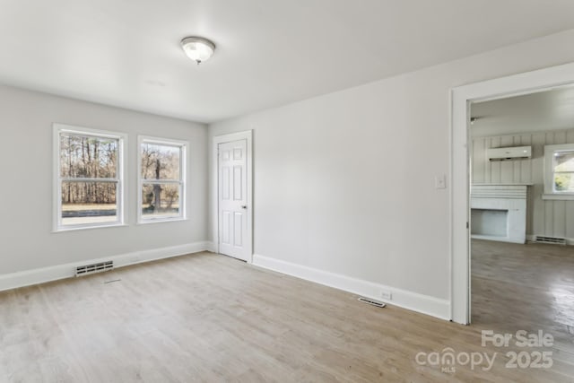 empty room with light wood-type flooring and a wall unit AC