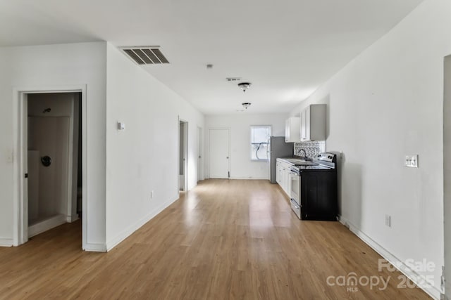 kitchen with decorative backsplash, sink, white cabinetry, light wood-type flooring, and stainless steel appliances