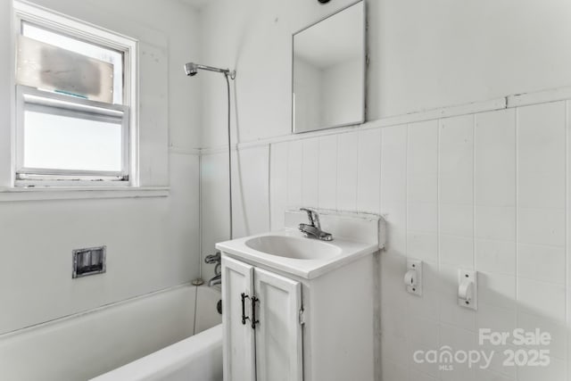 bathroom featuring backsplash, shower / tub combination, vanity, and tile walls