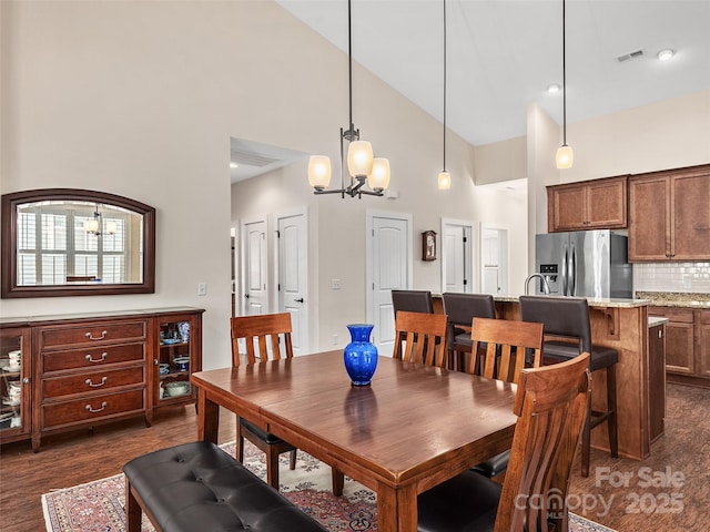 dining area featuring high vaulted ceiling, a notable chandelier, and dark hardwood / wood-style floors