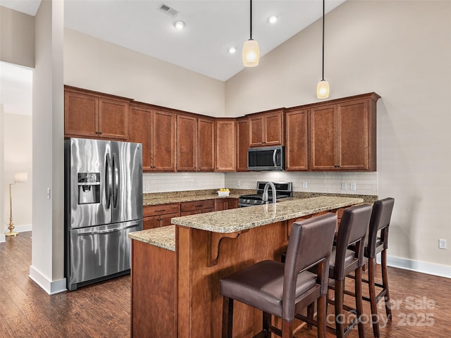 kitchen with high vaulted ceiling, pendant lighting, light stone counters, and appliances with stainless steel finishes