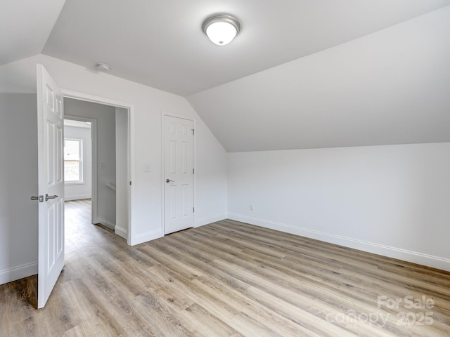 bonus room with light wood-type flooring and vaulted ceiling