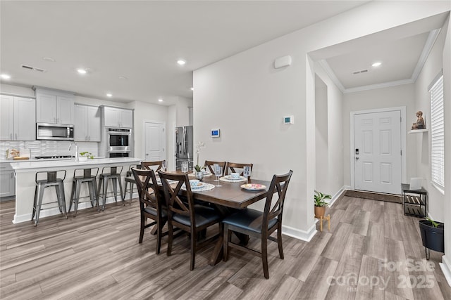 dining area featuring crown molding and light hardwood / wood-style flooring