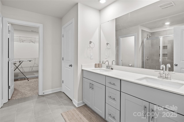 bathroom with a shower with door, vanity, and tile patterned flooring