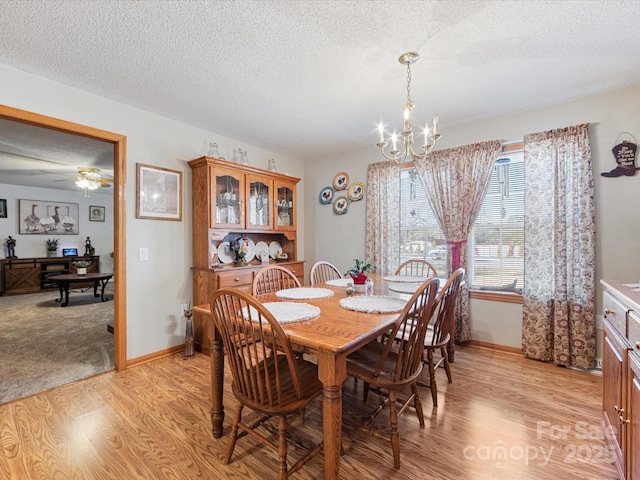 dining room featuring ceiling fan with notable chandelier, a textured ceiling, and light wood-type flooring