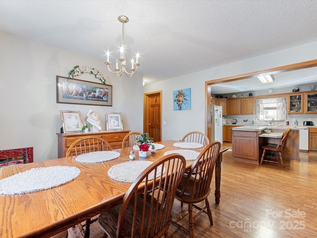 dining area featuring a notable chandelier, light hardwood / wood-style flooring, and a textured ceiling