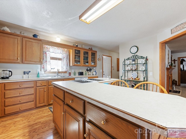 kitchen with a center island, light wood-type flooring, sink, and a textured ceiling