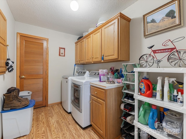 laundry room with cabinets, light hardwood / wood-style floors, washer and dryer, and a textured ceiling