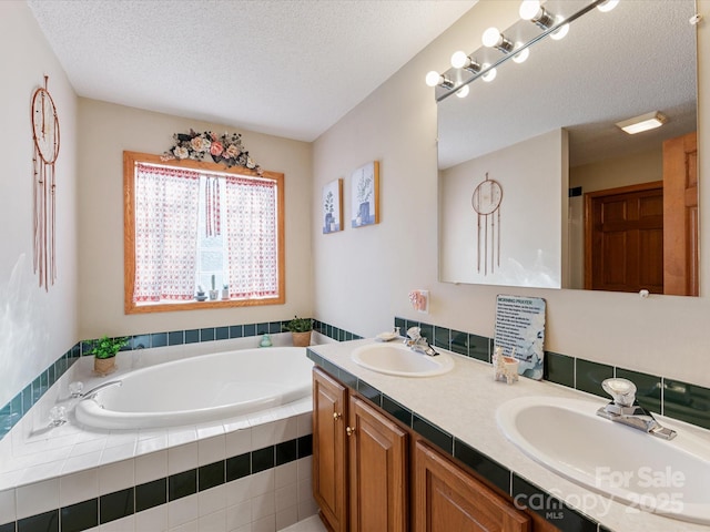 bathroom with vanity, a relaxing tiled tub, and a textured ceiling