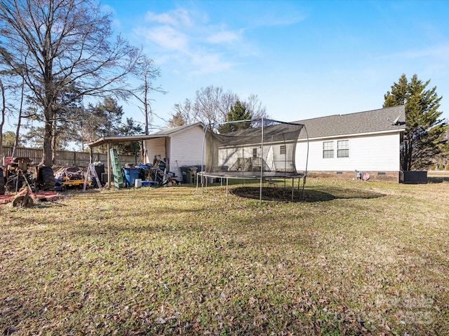 back of house featuring a trampoline and a yard