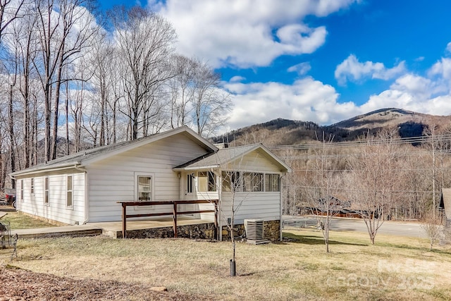 back of house with cooling unit, a yard, and a mountain view