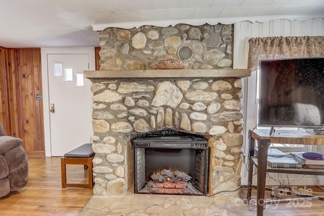 details featuring hardwood / wood-style floors, wood walls, ornamental molding, and a stone fireplace