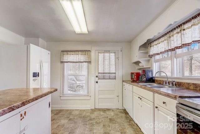 kitchen featuring sink, white appliances, white cabinets, and a wealth of natural light