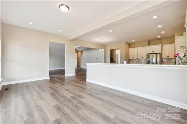 unfurnished living room with light wood-type flooring and beamed ceiling