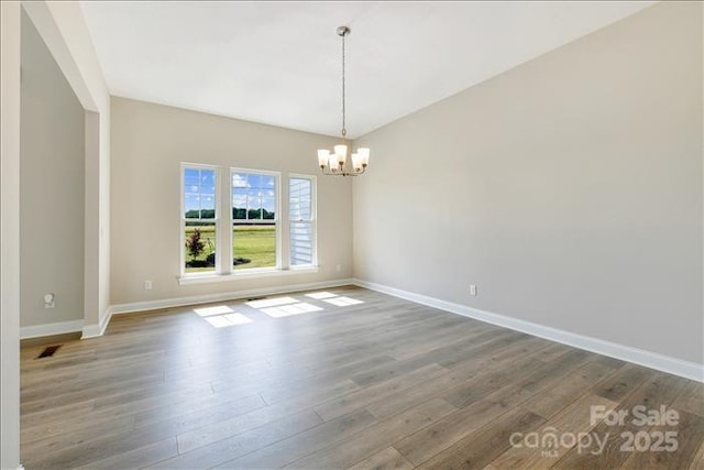 spare room featuring hardwood / wood-style flooring and a notable chandelier