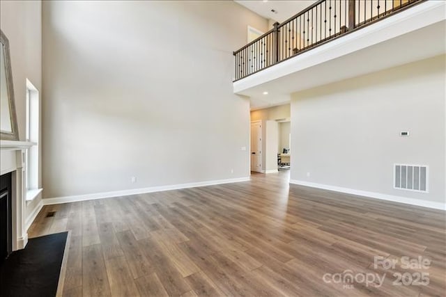 unfurnished living room featuring hardwood / wood-style floors and a towering ceiling