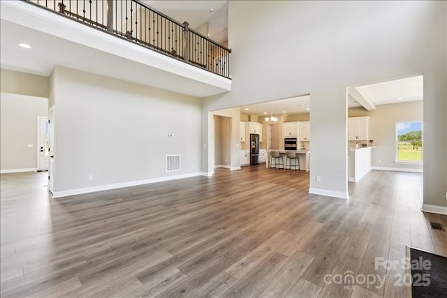 unfurnished living room featuring a high ceiling and hardwood / wood-style flooring