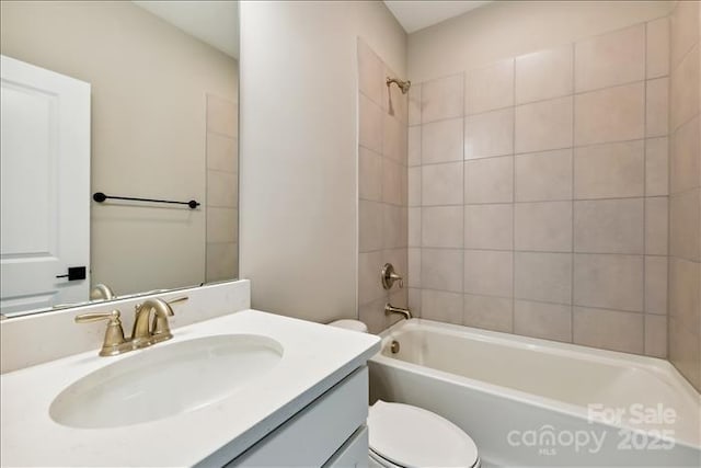 full bathroom with tiled shower / bath, vanity, and toilet