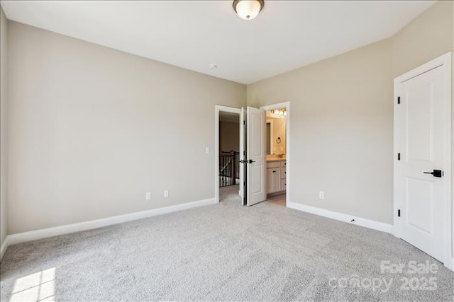 unfurnished bedroom with ensuite bathroom and light carpet