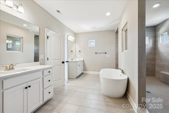 bathroom with plus walk in shower, tile patterned floors, a healthy amount of sunlight, and vanity