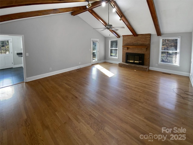 unfurnished living room with ceiling fan, vaulted ceiling with beams, a fireplace, and wood-type flooring