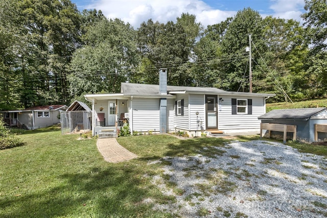 view of front of property featuring a porch, a storage unit, and a front lawn