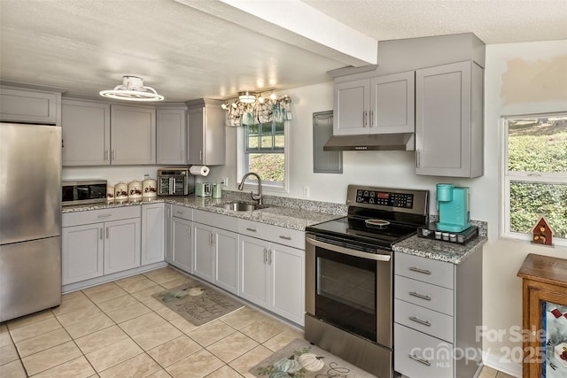 kitchen featuring light stone counters, a textured ceiling, stainless steel appliances, light tile patterned floors, and sink