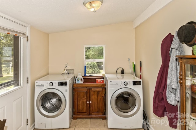 laundry room featuring washer and clothes dryer, a textured ceiling, light tile patterned floors, and cabinets