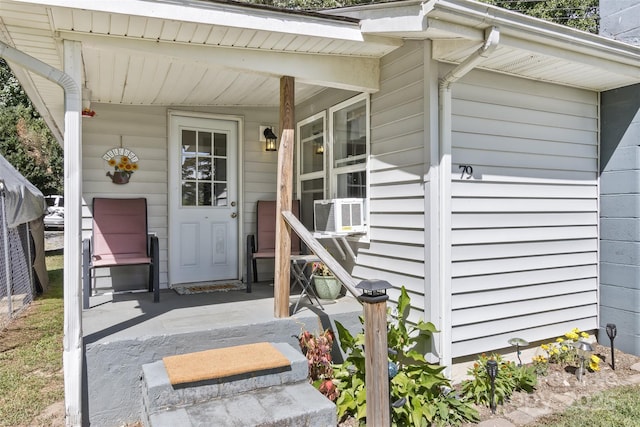 entrance to property featuring covered porch and cooling unit