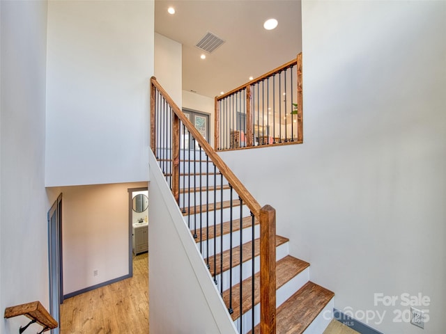 stairs with a high ceiling and wood-type flooring