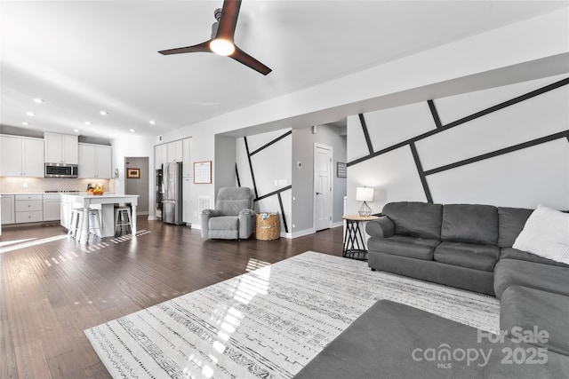 living room featuring ceiling fan and dark hardwood / wood-style floors