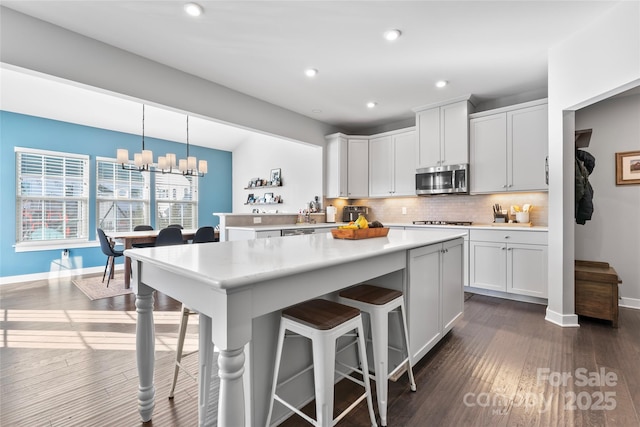 kitchen featuring a kitchen breakfast bar, decorative backsplash, pendant lighting, and white cabinets