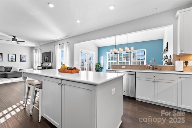 kitchen with tasteful backsplash, decorative light fixtures, dark hardwood / wood-style flooring, stainless steel dishwasher, and white cabinets