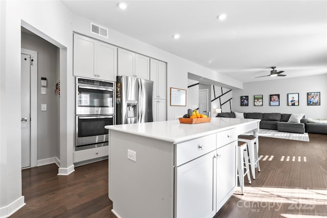 kitchen with white cabinets, stainless steel appliances, a breakfast bar area, and a kitchen island