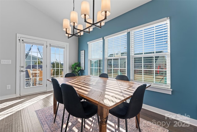 dining space with wood-type flooring, a chandelier, and vaulted ceiling