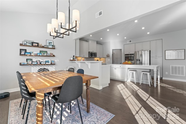 dining space featuring dark wood-type flooring and an inviting chandelier