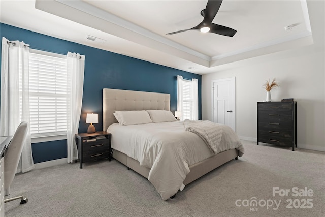 bedroom with ceiling fan, light colored carpet, and a tray ceiling