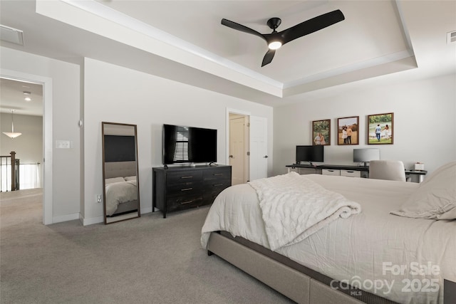 carpeted bedroom with ceiling fan and a tray ceiling