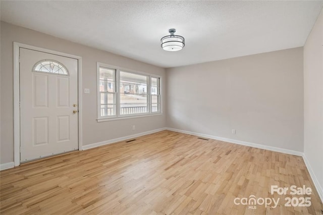 entryway with a textured ceiling and light wood-type flooring