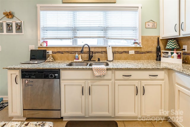 kitchen with sink, light tile patterned floors, dishwasher, light stone counters, and decorative backsplash