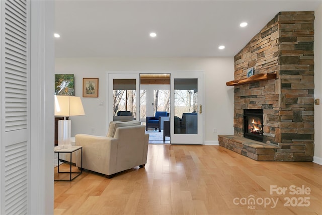 living room featuring light wood-type flooring, a fireplace, recessed lighting, and baseboards
