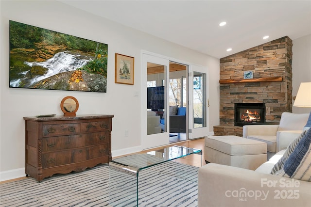 living area featuring baseboards, a stone fireplace, vaulted ceiling, and recessed lighting