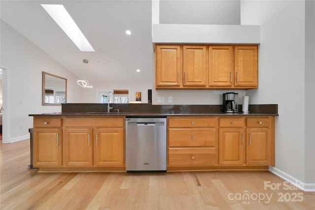 kitchen with stainless steel dishwasher, a skylight, vaulted ceiling, light wood finished floors, and a peninsula